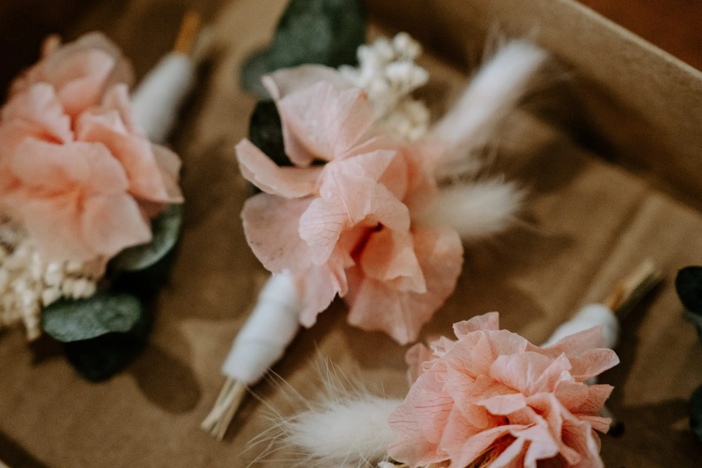 Prendidos de claveles rosas y espigas secas sobre una bandeja de madera