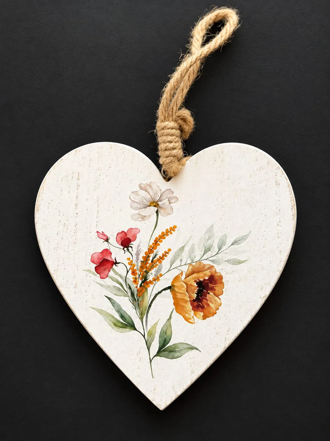 Corazón de madera blanco con flores pintadas en rojo, naranja y verde, colgado de un cordel de yute.