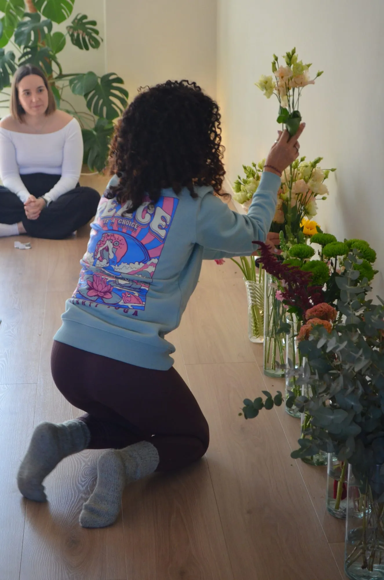 Una participante con sudadera azul, de rodillas, elige una alstroemeria de los jarrones